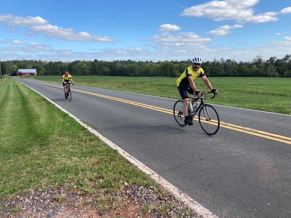 two cyclists on rural road wearing yellow jerseys